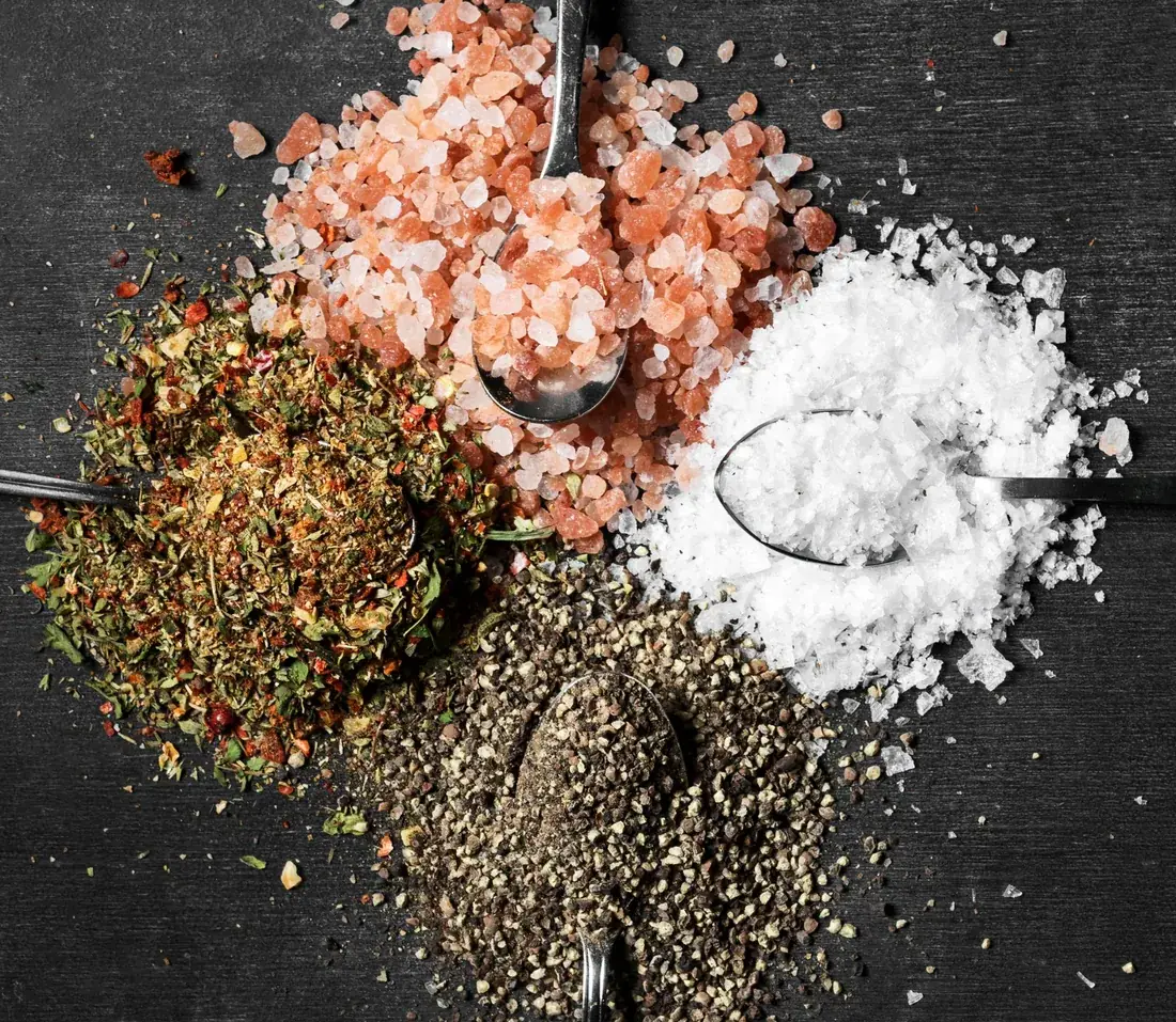 Sais e temperos brasileiros em colheres sobre mesa escura